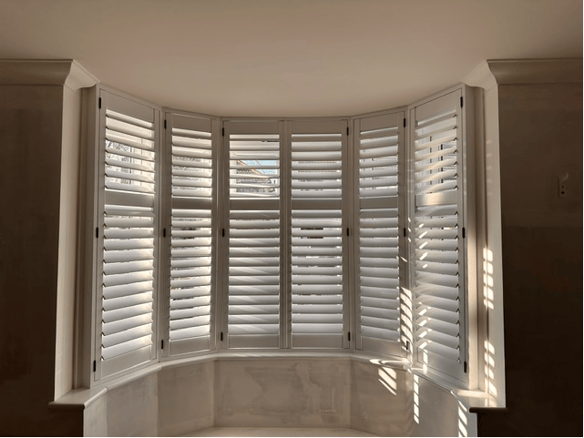 Elegant white shutters in a curved bay